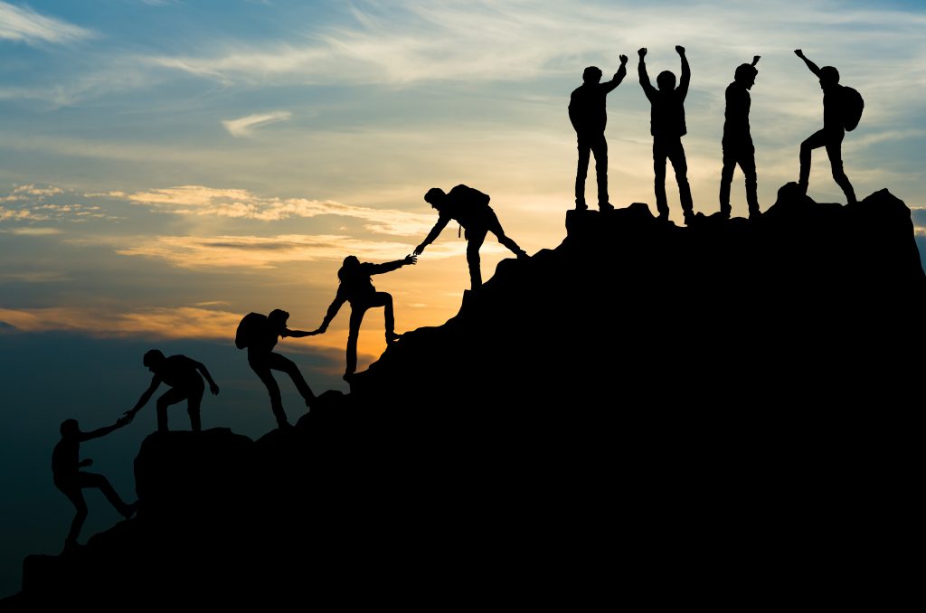 An image of a team of people reaching the peak of a mountain